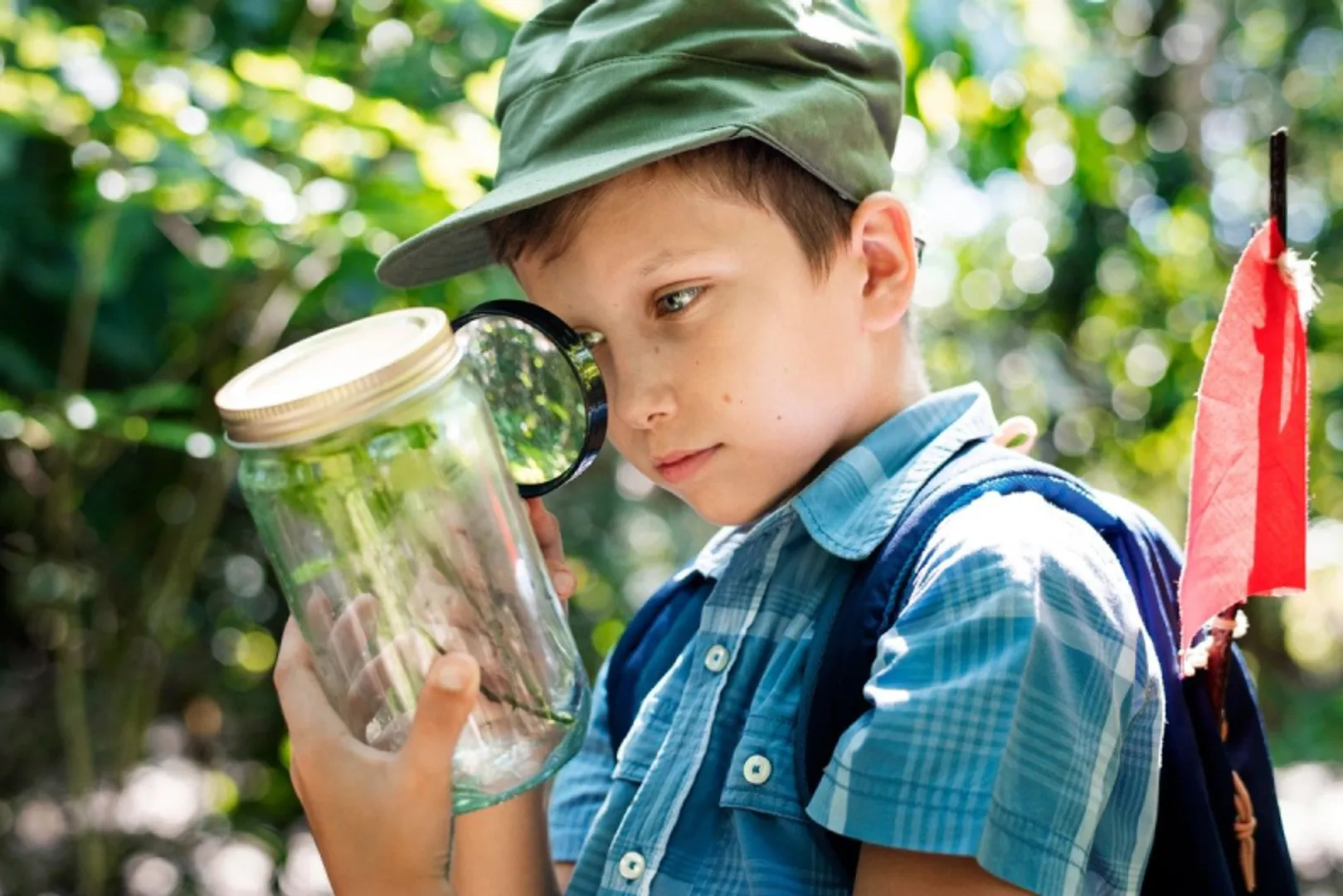 Photo of young boy examining insect in jar while on eco-hike