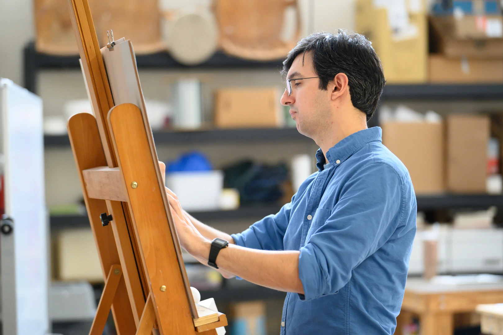 Professor Joseph Kameen painting at an easel in his studio