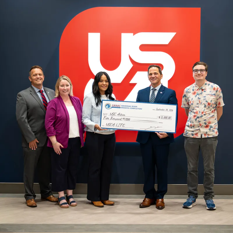 Savannah River Mission Completion donated $5,000 to the USCA LIFE program and welcomed back LIFE student worker Jesse Reyes into the SRMC Laboratories. From left, USCA Vice Chancellor Development & Alumni Affairs Daniel Elwell, Sr., USCA LIFE Director Dr. Melissa Martin, SRMC Laboratories Director Melissa Santaella-Ramos, USCA Chancellor Dr. Daniel Heimmermann, and USCA LIFE Student Jesse Reyes.