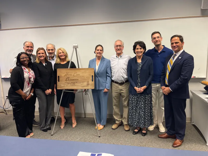 Cato's family and wife, Lisa Cato (in the middle), stand alongside Chancellor Daniel Heimmerman (far right) and student speaker, Justice English (far left).