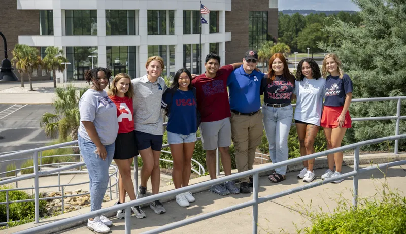USCA student pose for photo with the Convocation Center in the background