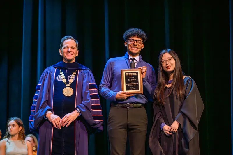 Ian Dumas, center, receives the Outstanding Student in Accounting award from Chancellor Daniel Heimmermann, left, and Dr. Yu Cao, associate professor in the USCA School of Business Administration. USCA held its annual Academic Honors Ceremony on May 5 in the Etherredge Center, recognizing students from across the campus for their academic excellence.